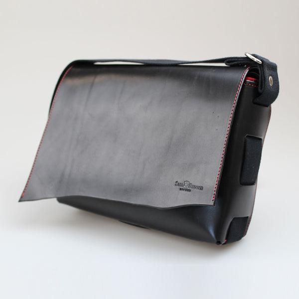 Black full grain leather Bag with red stitch around edge of long flap and finest red leather lining with magnetic clasp. Made by Sam Brown London